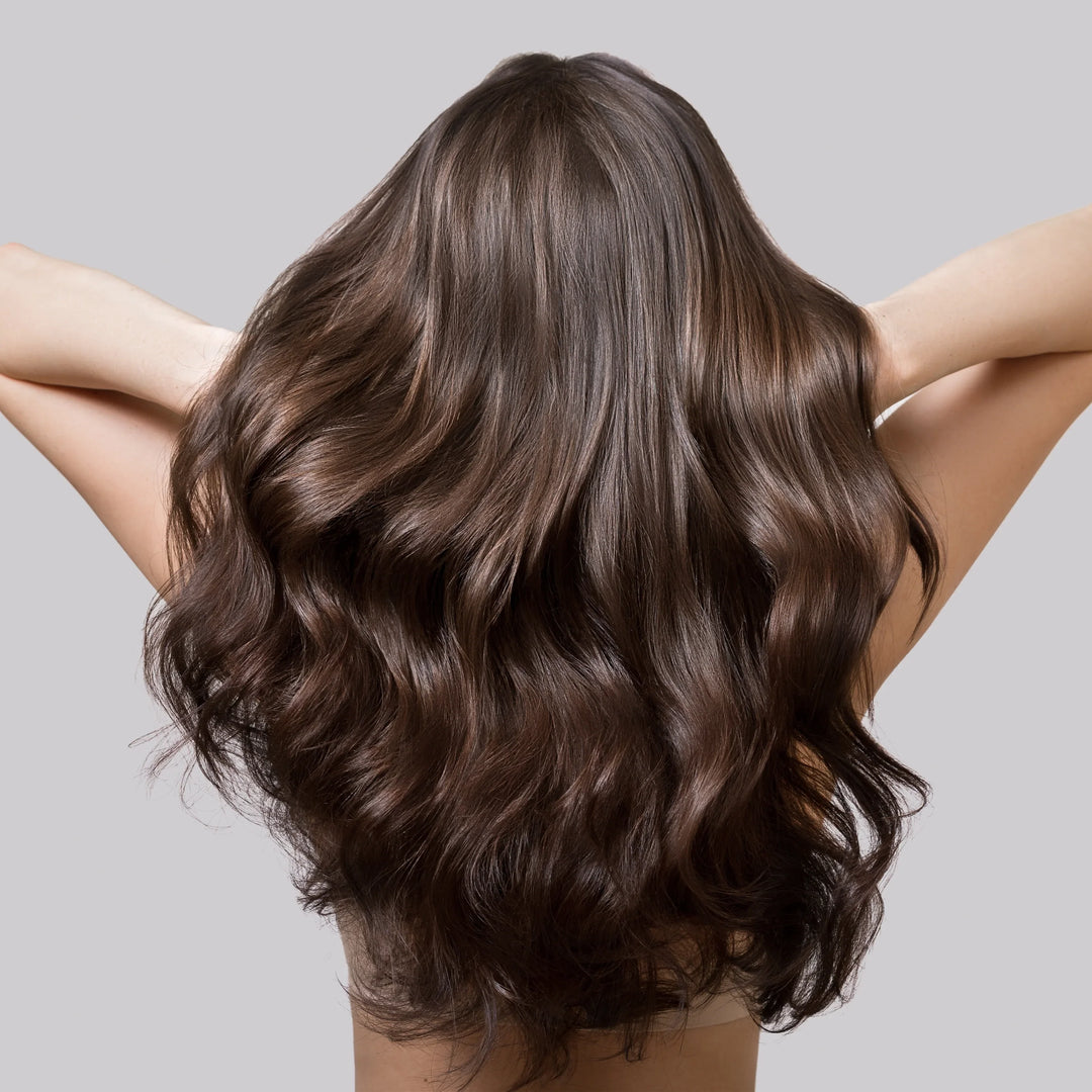 Una donna con capelli sani e luminosi, che tiene in mano una confezione di integratori di biotina Matt