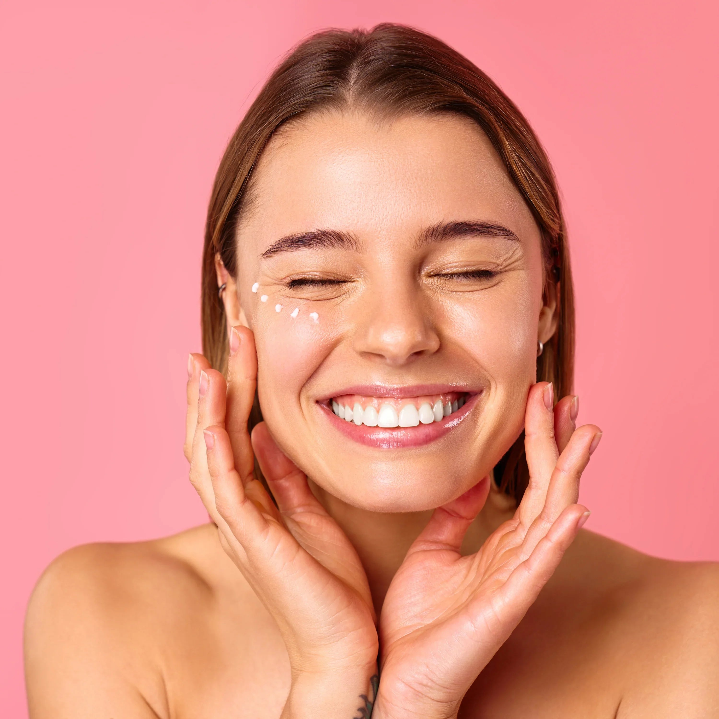 Una donna applica una crema contorno occhi, con lo sfondo sfocato di un bagno luminoso.