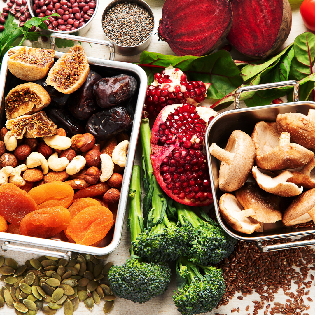 prodotti naturali che contengono ferro su un tavolo, con accanto un bicchiere d'acqua e alcuni frutti rossi ricchi di vitamina C